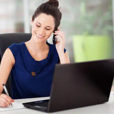 Photo shows receptionist on phone and laptop, helping schedule visits with chiropractic doctors near me