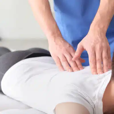 Chiropractor applies pressure on patient’s back during treatment, addressing concerns like can a chiropractor help with sciatica