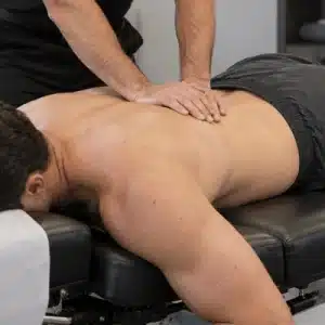 A car accident chiropractor provides hands-on treatment to a patient’s back while the patient lies on a chiropractic table