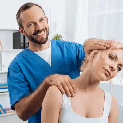 Chiropractor smiling while adjusting female patient’s neck to improve mobility, chiropractor for rheumatoid arthritis
