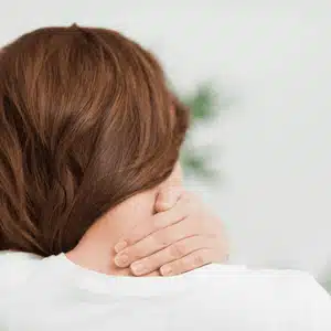 Woman holding neck with tension, may benefit from chiropractic for neck pain treatment
