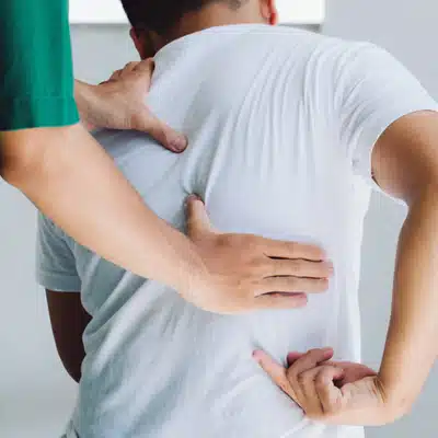 Hands examine patient's back while he bends, documenting spinal curvature during clinical scoliosis assessment today