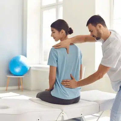 Therapist measures shoulder and back position during scoliosis treatment near me exam on table