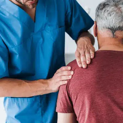 Clinician assesses patient’s shoulder and upper back, planning pinched nerve treatment and recovery steps