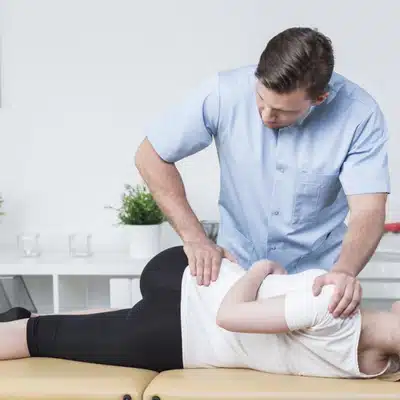 Chiropractor performing spinal adjustment on a patient lying on their side in a treatment room