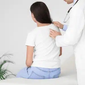 Scoliosis chiropractor checks upper spine of patient to evaluate alignment and muscle tension imbalance