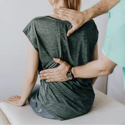 Therapist examines patient’s back with hands during visit, providing degenerative disc disease treatment assessment guidance