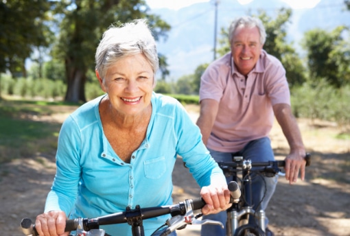 senior-couple-cycling-sciatica-relief Smiling senior couple cycling on a tree-lined path after sciatica relief